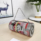 Cylinder-shaped beaded handbag with colorful pop art design, chain handle, on wooden table.