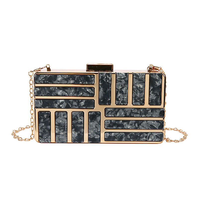 Gold clutch with geometric black textured panels and a chain strap.