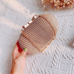 Gold textured clutch with a bow clasp and chain, held on a white patterned background.