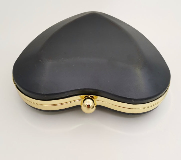 Black heart-shaped case with a gold clasp and trim, set against a white background.