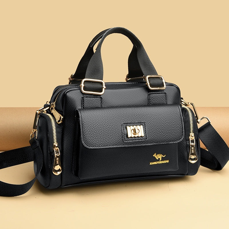 Black handbag with gold zippers and buckles, featuring a textured flap and adjustable strap.