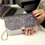Silver glitter clutch with a gold clasp, held by a person with red nails, near a laptop.