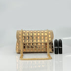Golden studded handbag with chain strap beside two black lipstick tubes on a gray background.