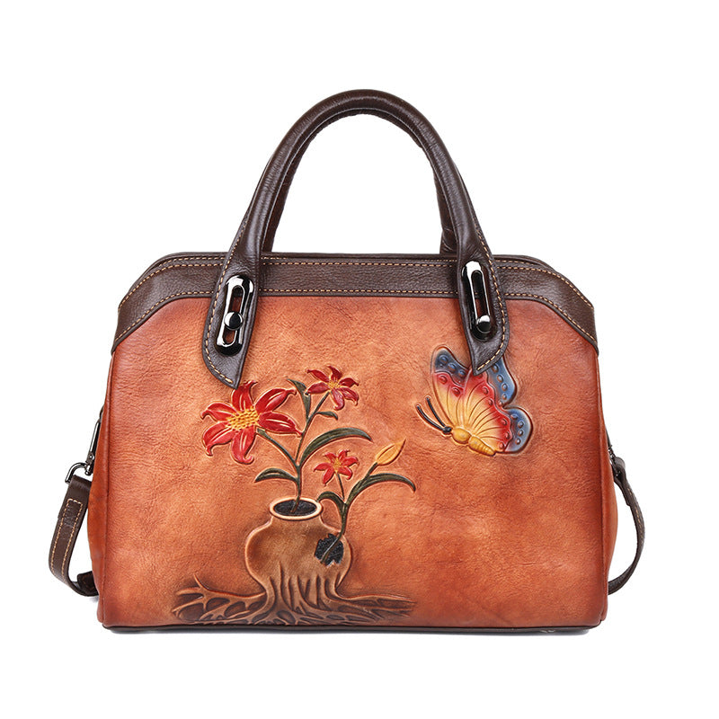 Brown handbag with dark handles, embossed red flowers, and a colorful butterfly design.