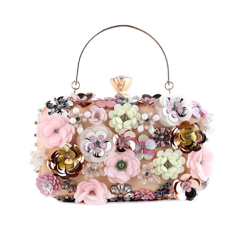 Elegant clutch with colorful 3D floral designs, pearls, and a gold handle on a beige background.