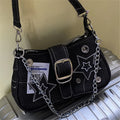Black denim bag with star patches, chain strap, buckle, and silver accents on a gray surface.