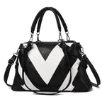 Black and white handbag with chevron pattern, dual handles, and detachable shoulder strap.