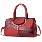 Red leather handbag with a crocodile pattern, gold buckle, and dual top handles.